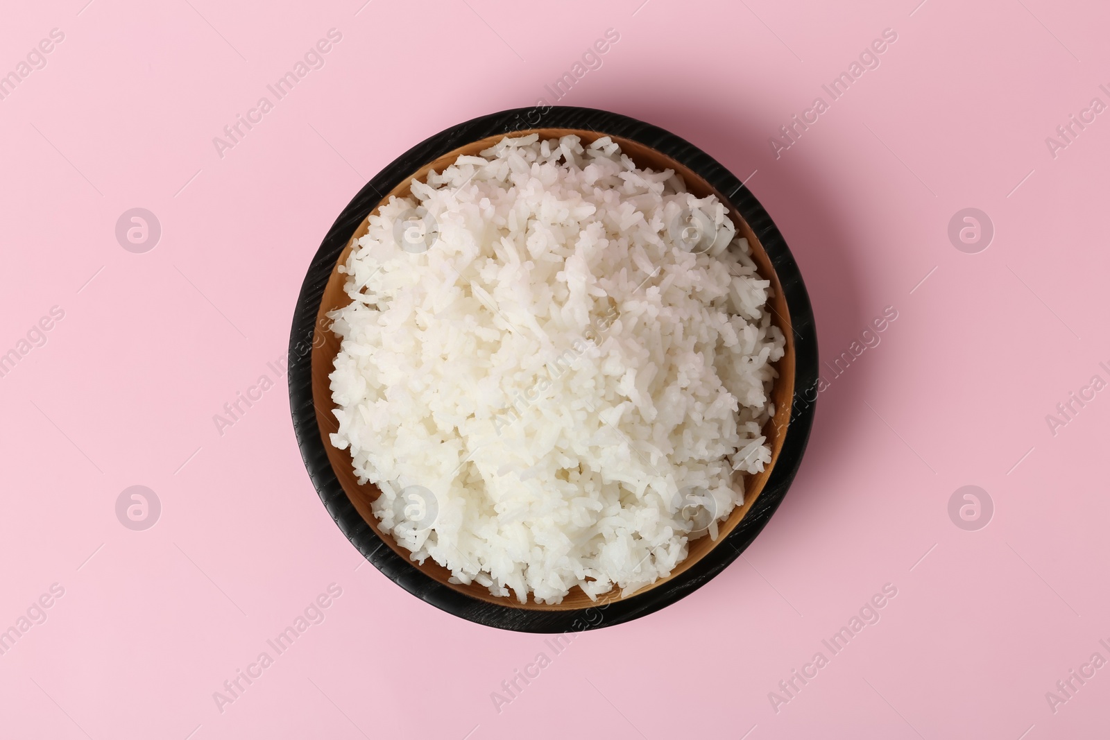 Photo of Bowl of boiled rice on color background, top view