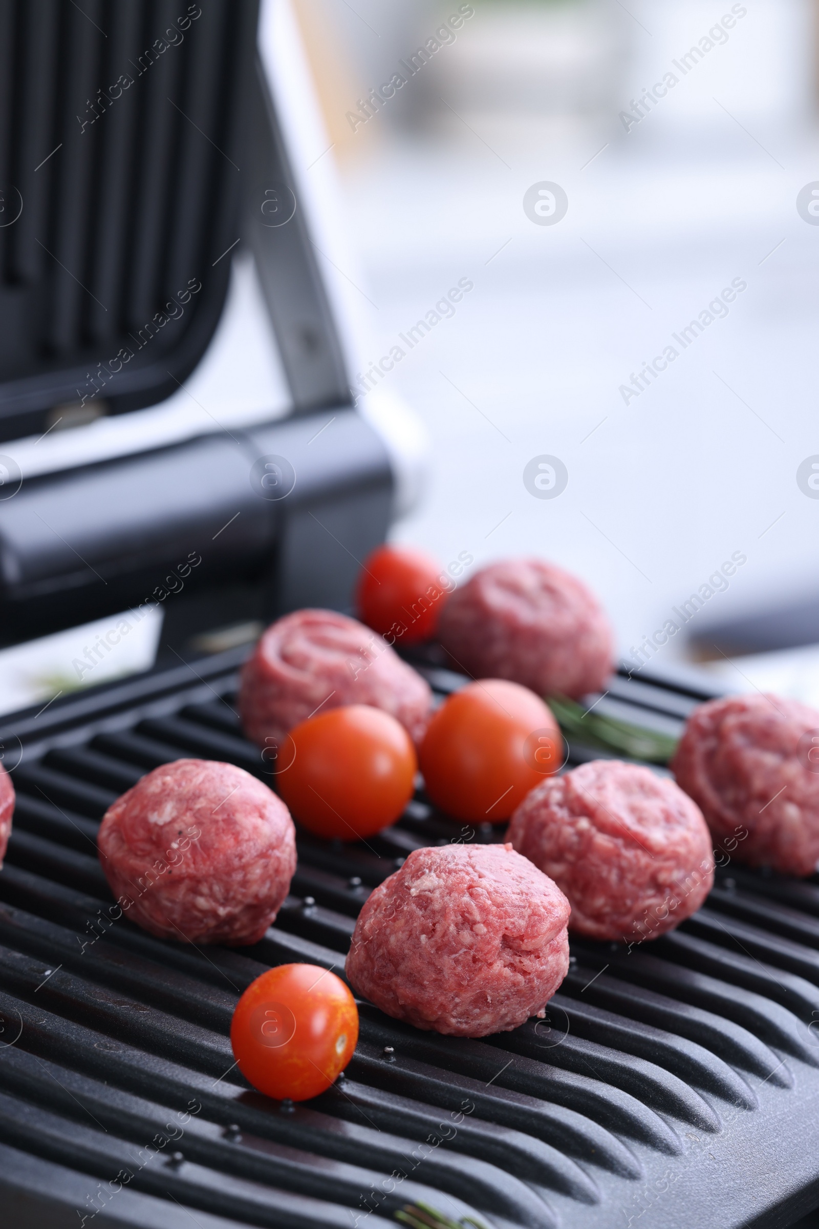 Photo of Meatballs and tomatoes on electric grill, closeup