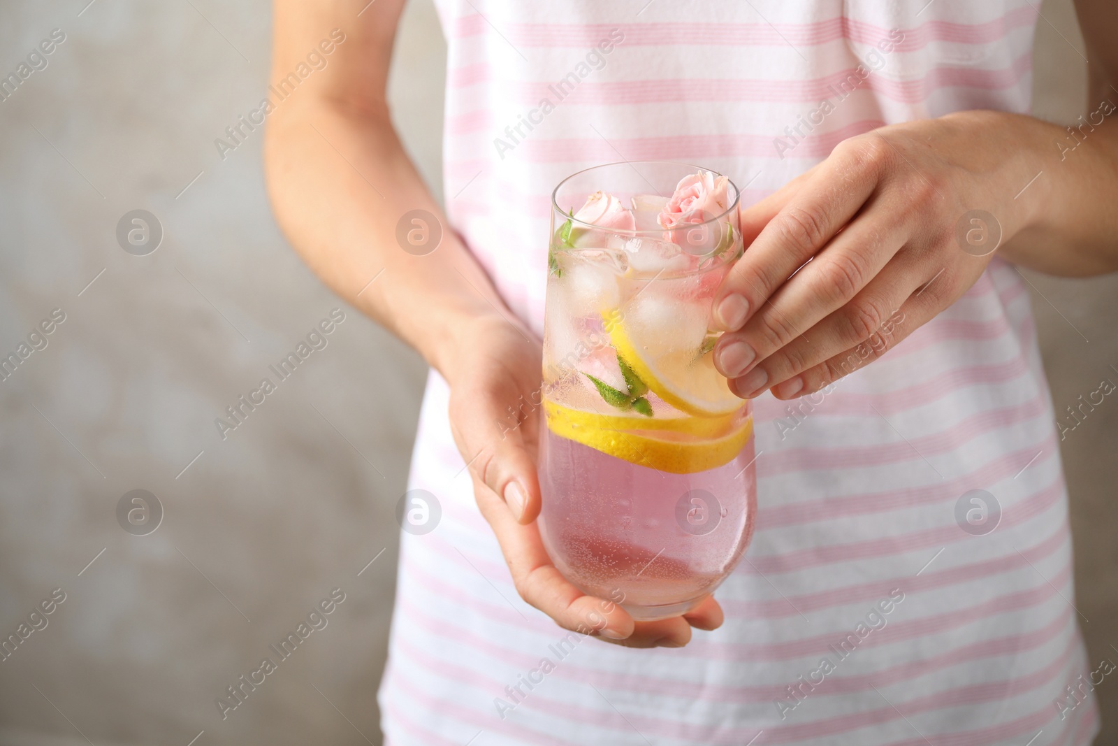 Photo of Young woman with glass of tasty refreshing drink on beige background, closeup