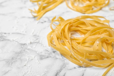 Photo of Raw egg noodles on marble table, closeup with space for text