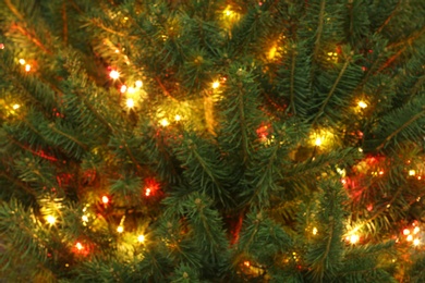 Photo of Blurred view of glowing bright fairy lights on Christmas tree