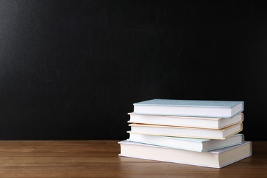 Stack of hardcover books on table against black background, space for text