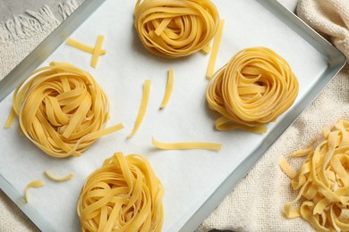 Photo of Tagliatelle pasta in baking pan on table, flat lay
