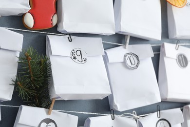 Photo of Advent calendar with gifts hanging on grey wall, closeup. Christmas season