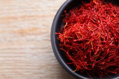 Photo of Dried saffron in bowl on wooden table, top view. Space for text