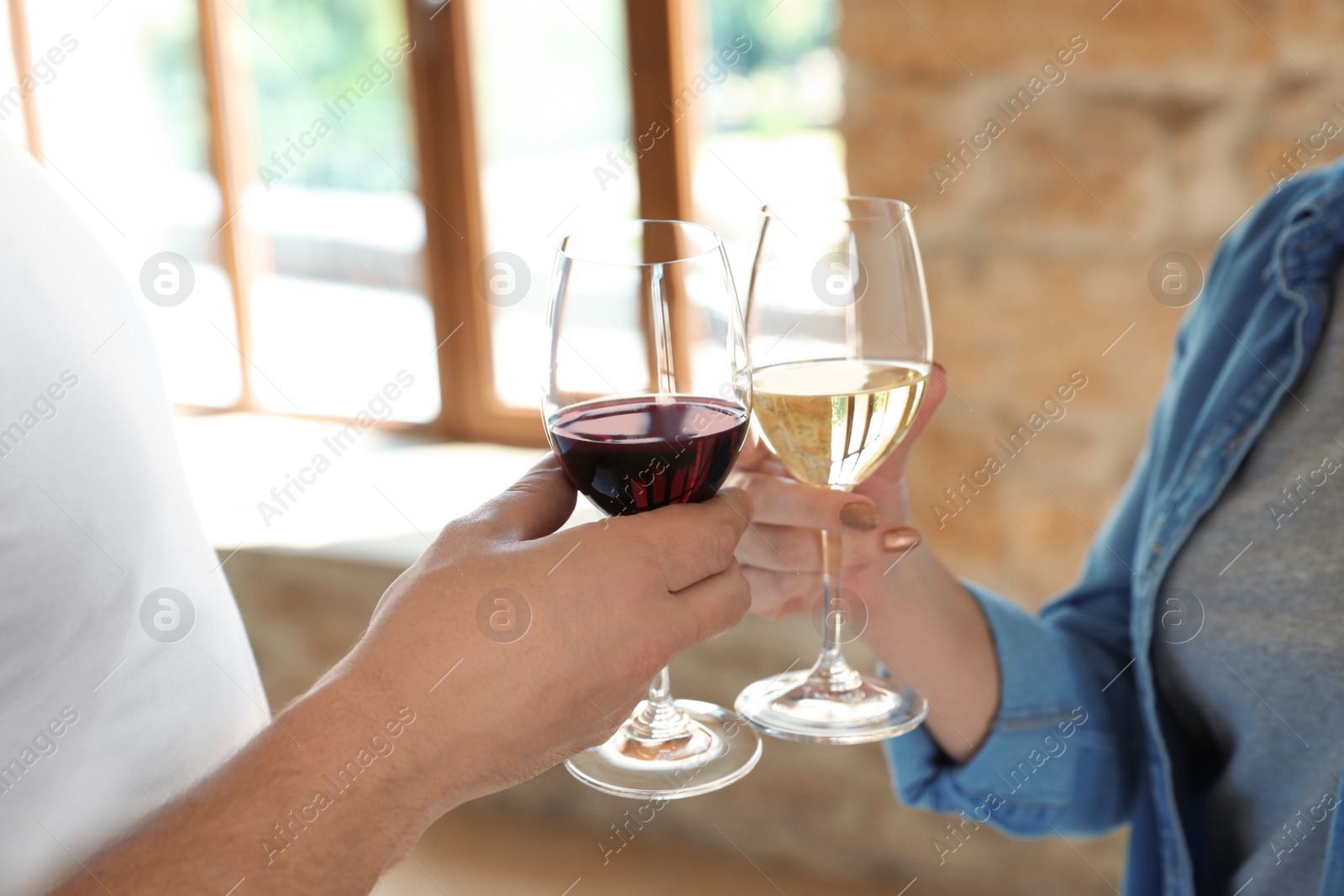 Photo of Couple with glasses of white and red wines indoors, closeup