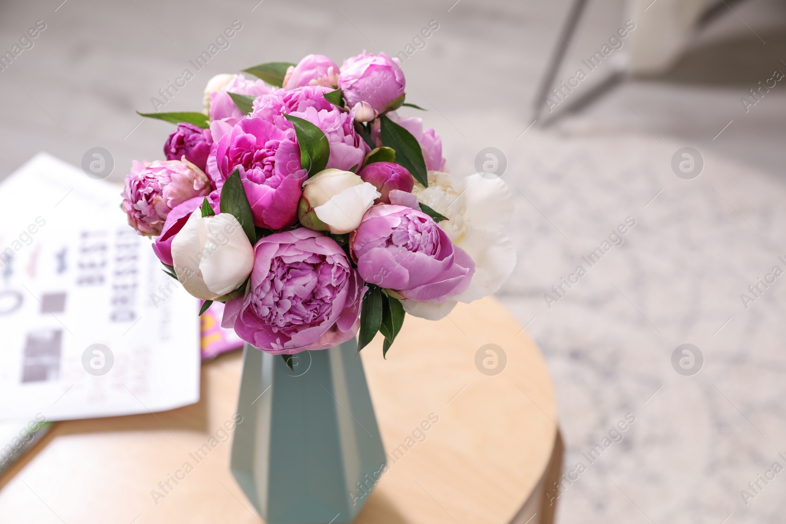 Photo of Vase with bouquet of beautiful peonies on table in room, space for text