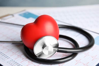 Stethoscope, red heart and cardiogram on table. Cardiology concept