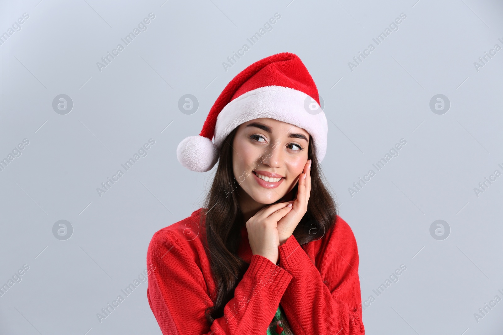 Photo of Beautiful woman wearing Santa Claus hat on light grey background