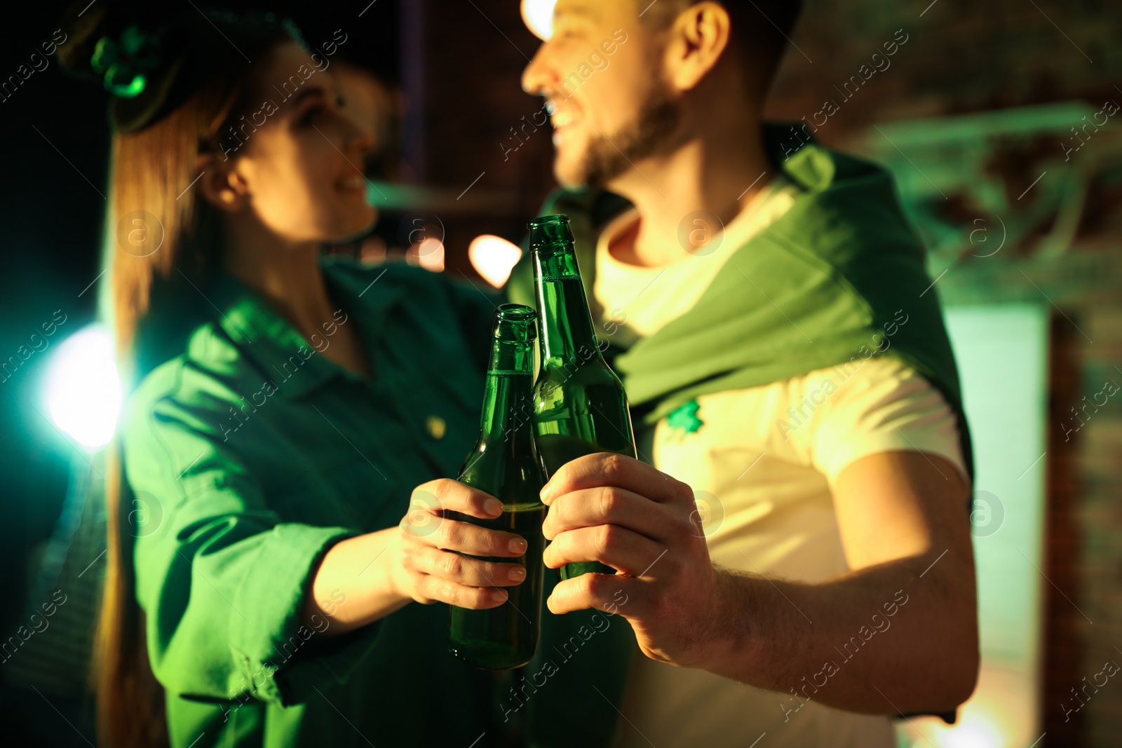 Photo of Couple with beer celebrating St Patrick's day in pub, focus on hands