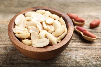 Photo of Fresh peanuts in bowl on wooden table, closeup