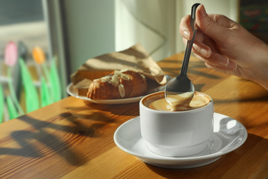 Photo of Woman with cup of fresh aromatic coffee at table in cafe