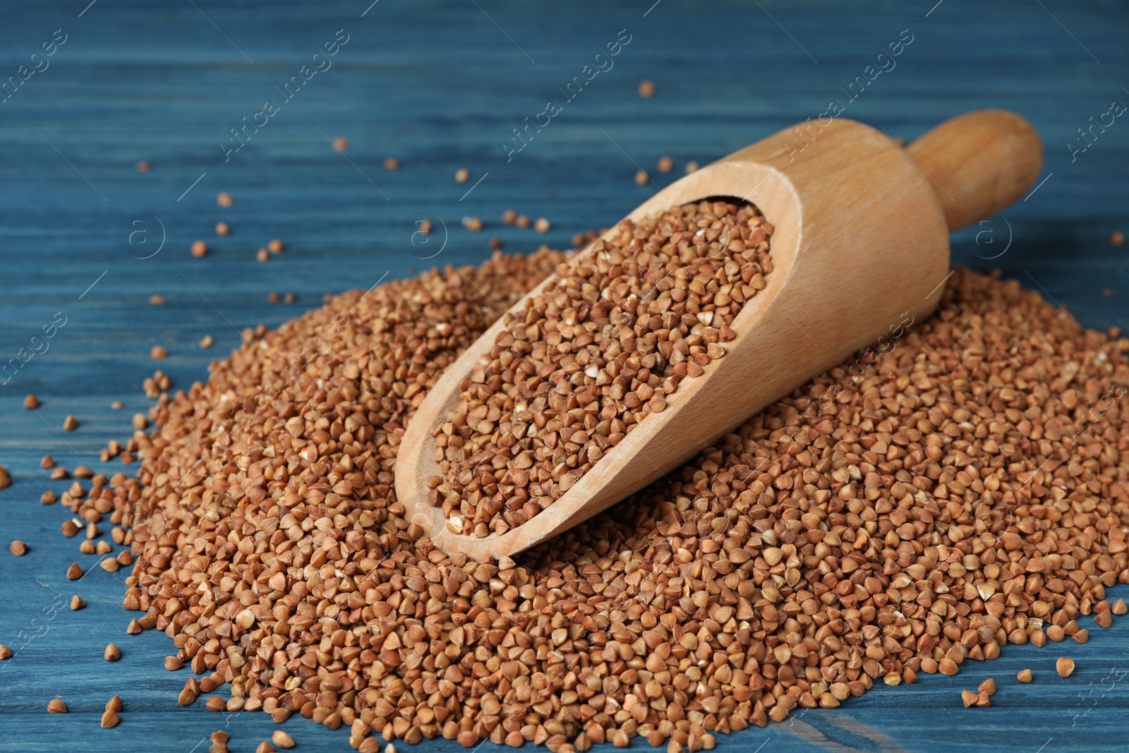 Photo of Wooden scoop with uncooked buckwheat on table