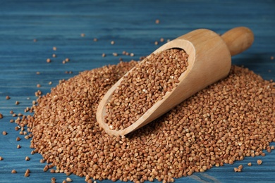 Photo of Wooden scoop with uncooked buckwheat on table