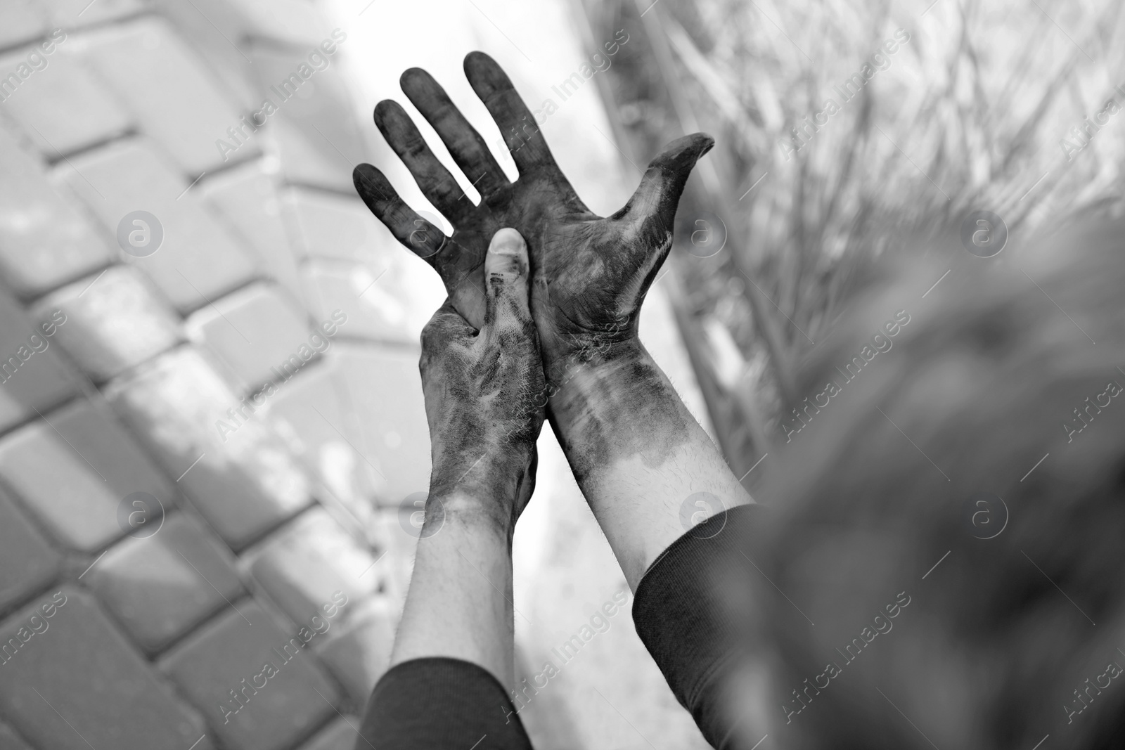 Photo of Dirty worker on blurred background, closeup of hands. Black and white effect