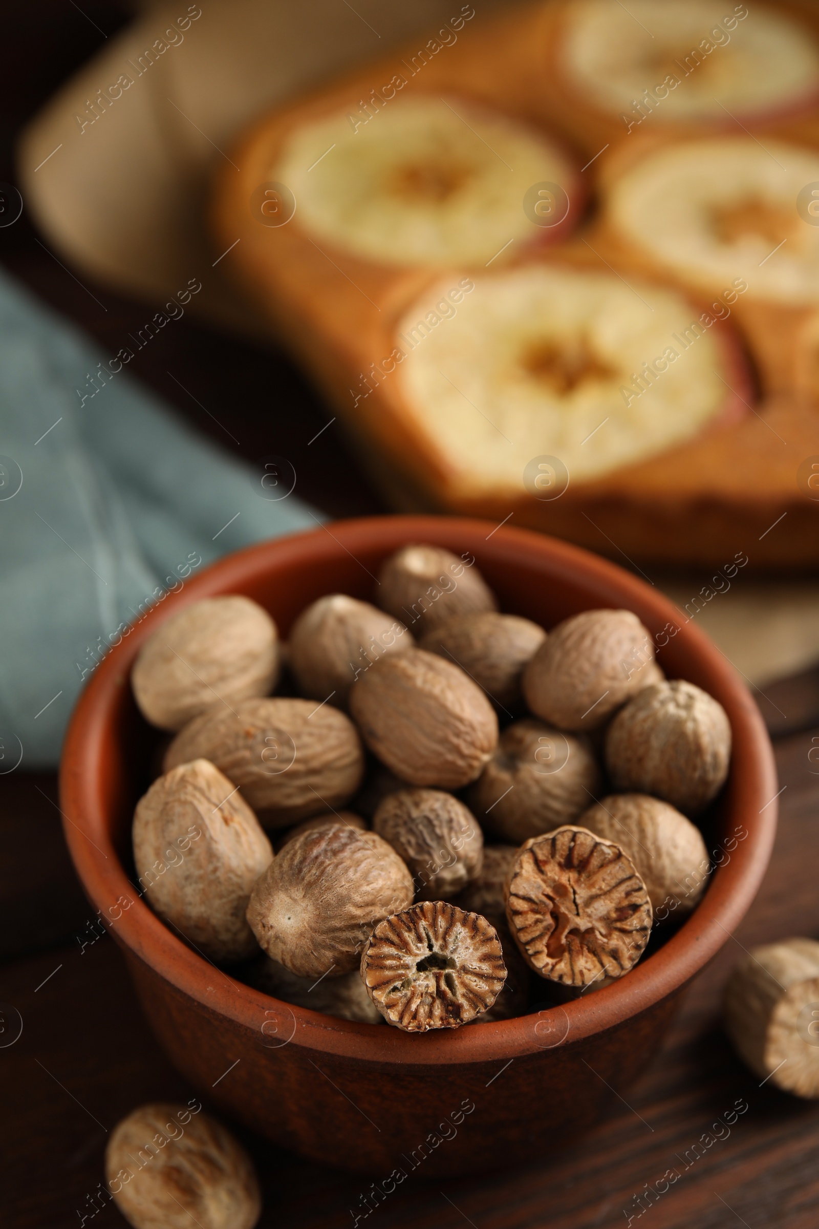 Photo of Nutmeg seeds and tasty apple pie on wooden table