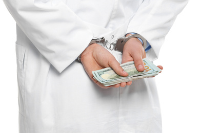 Doctor in handcuffs with bribe on white background, closeup. Corrupted medicine