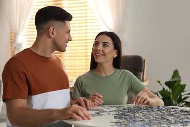 Happy couple playing with puzzles at home