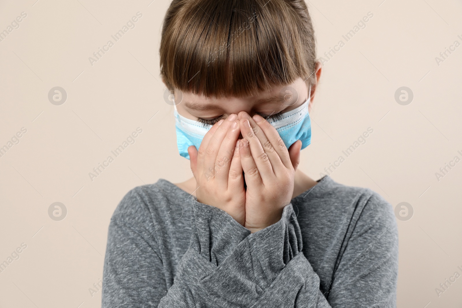 Photo of Little girl in medical mask on beige background. Virus protection