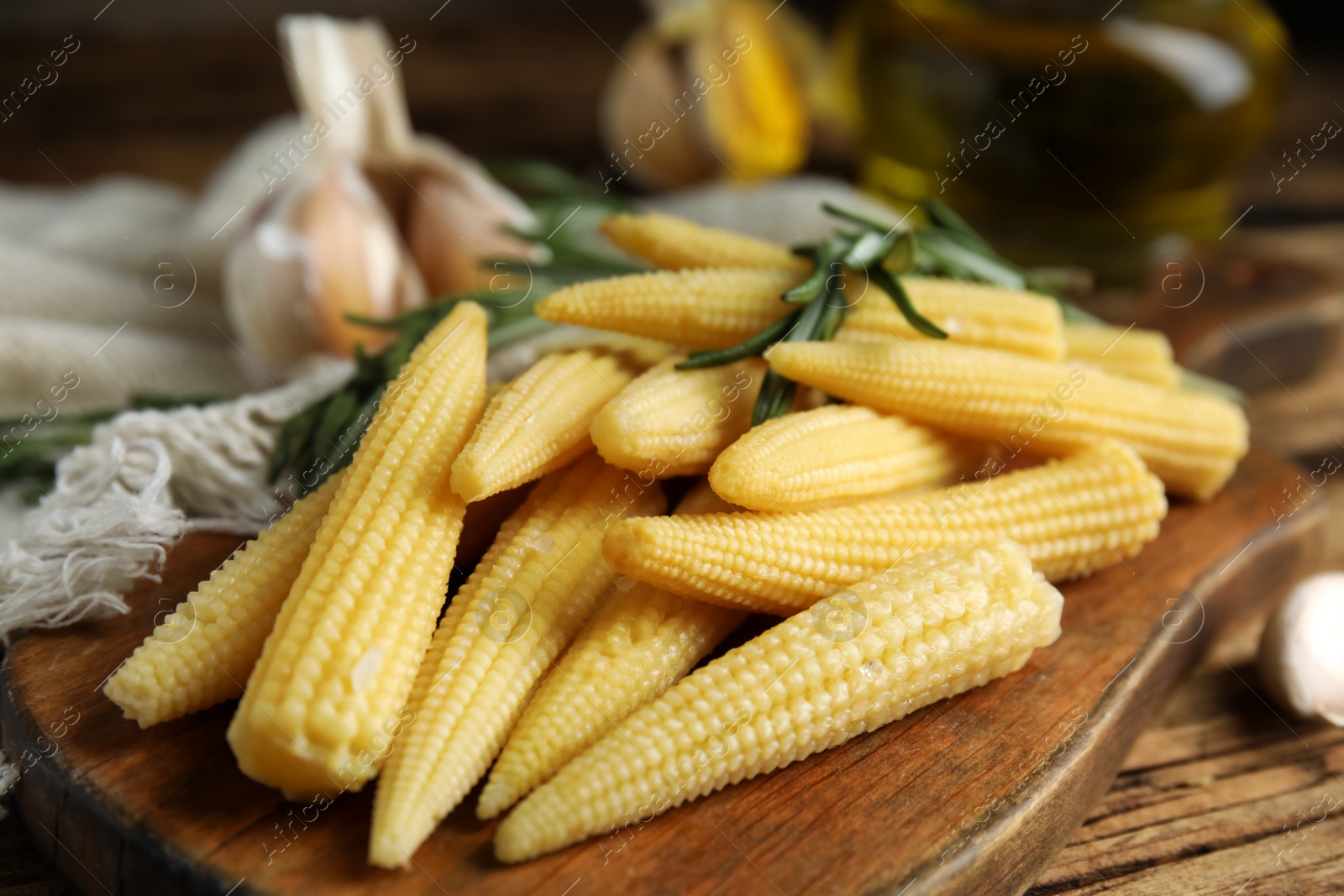 Photo of Fresh baby corn cobs on wooden table, closeup