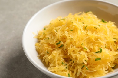 Photo of Bowl with cooked spaghetti squash on table, closeup