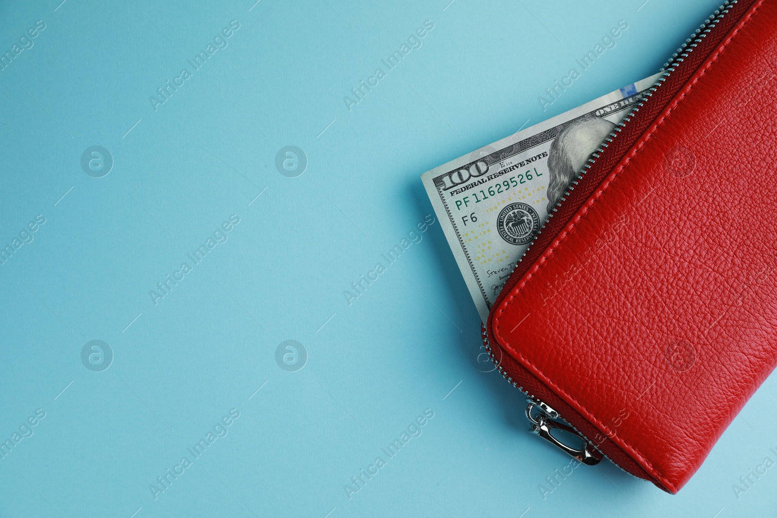 Photo of One stylish leather purse with money on light blue background, top view. Space for text