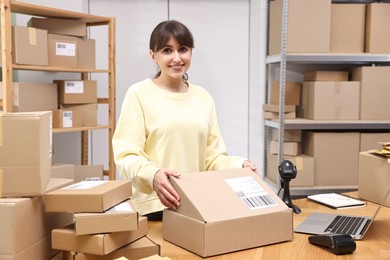 Photo of Post office worker packing parcel at wooden table indoors