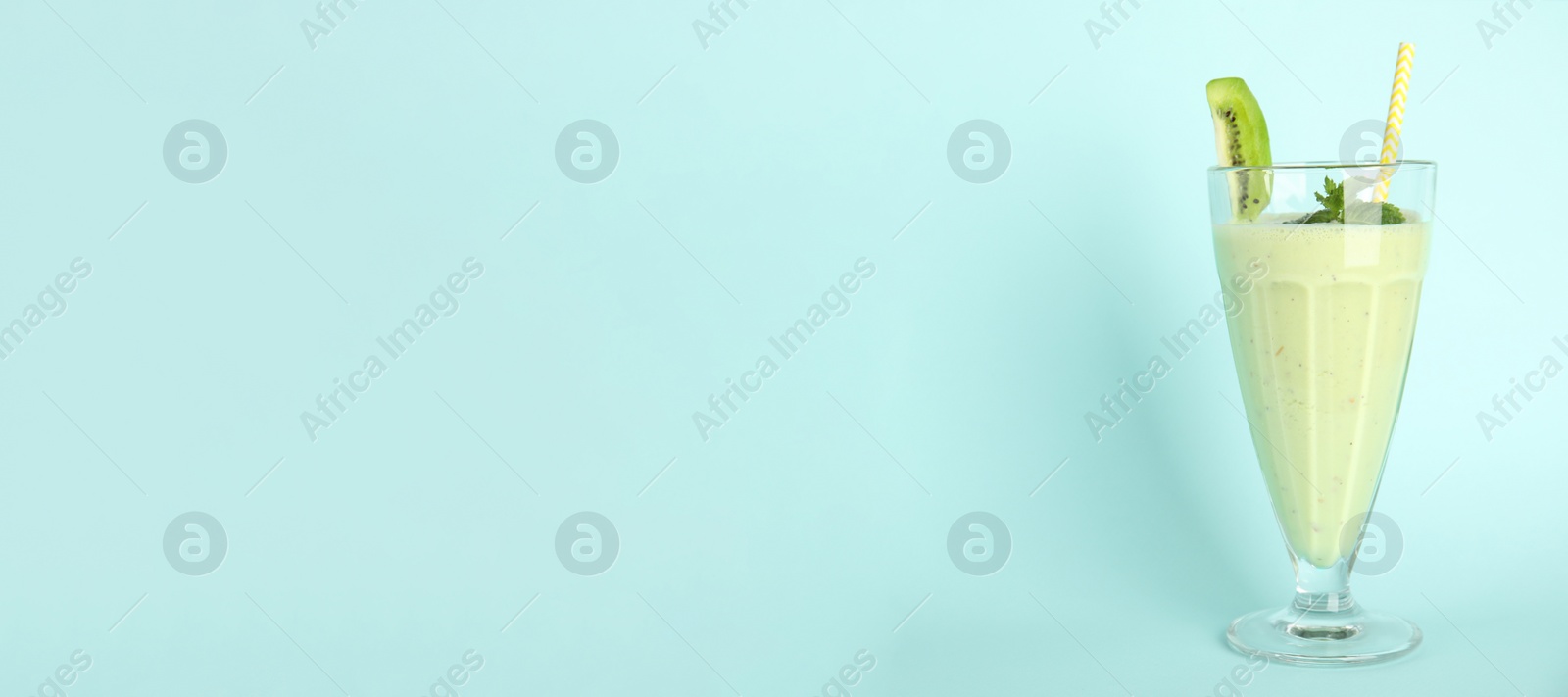 Photo of Tasty fresh milk shake with kiwi on light blue background. Space for text