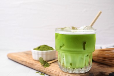 Photo of Glass of tasty iced matcha latte on wooden board, closeup. Space for text