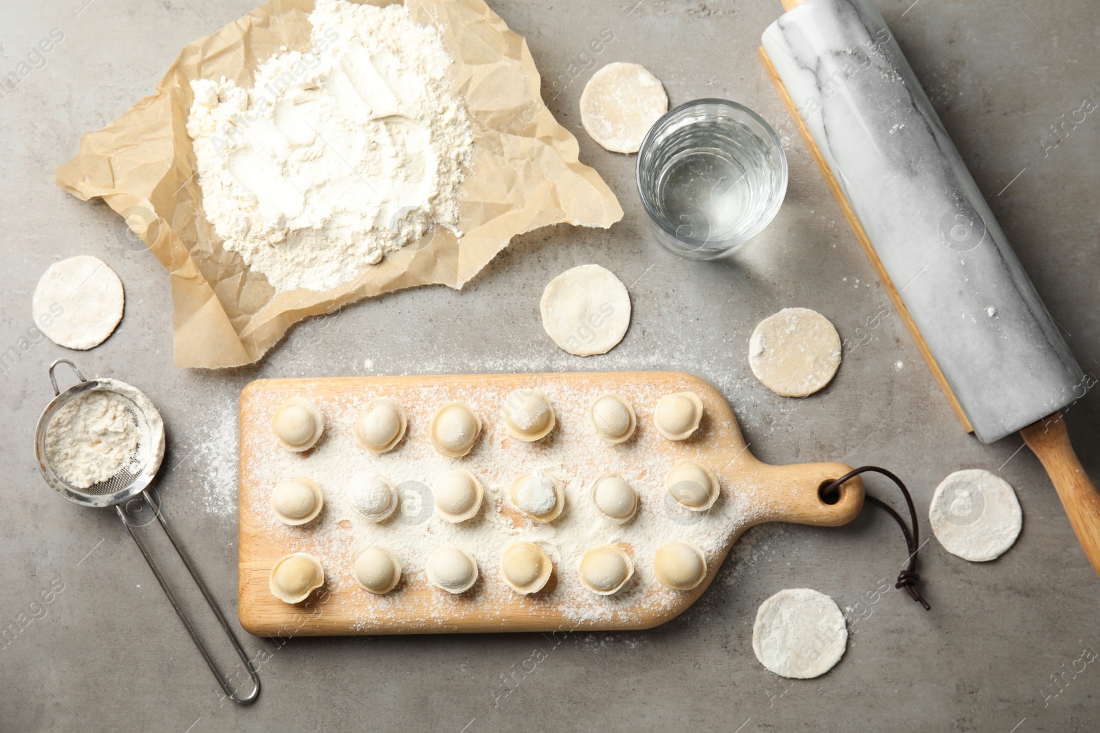 Photo of Flat lay composition with raw dumplings on grey background. Process of cooking