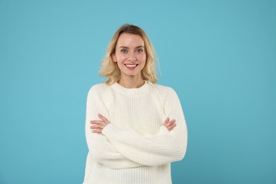 Photo of Happy woman in stylish warm sweater on light blue background