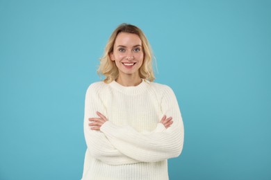 Happy woman in stylish warm sweater on light blue background