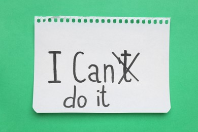 Motivation concept. Changing phrase from I Can't Do It into I Can Do It by crossing out letter T on green background, top view