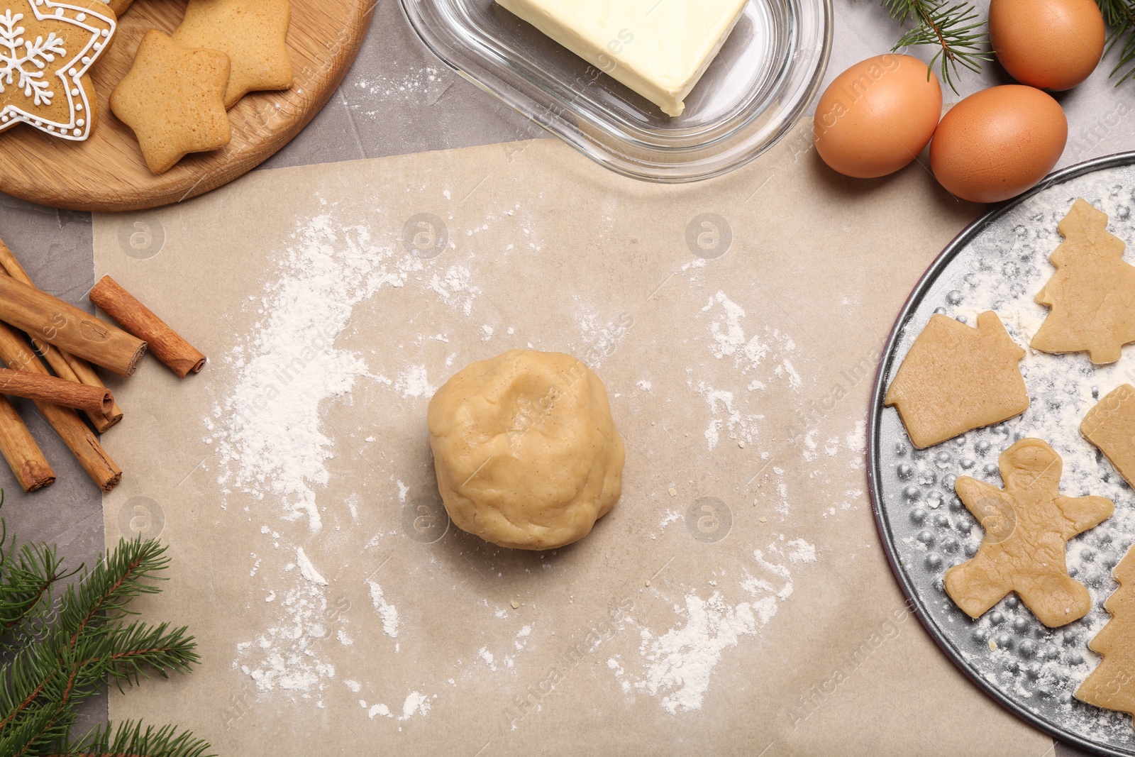 Photo of Making Christmas cookies. Flat lay composition with ingredients and raw dough on grey table