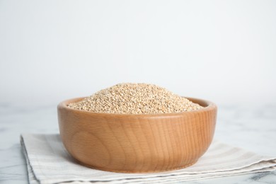 Photo of Wooden bowl with white quinoa on table. Space for text