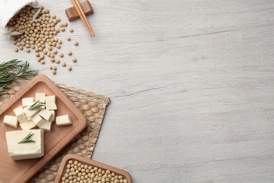 Pieces of delicious tofu with rosemary and soy on white table, flat lay, Space for text