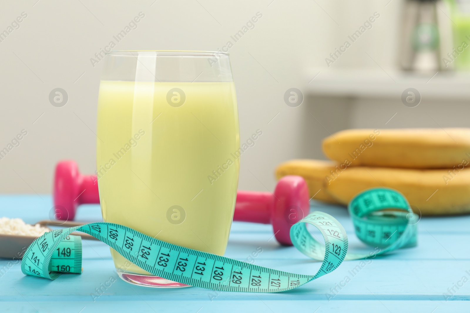 Photo of Tasty shake and measuring tape on light blue wooden table, closeup. Weight loss