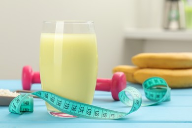Photo of Tasty shake and measuring tape on light blue wooden table, closeup. Weight loss