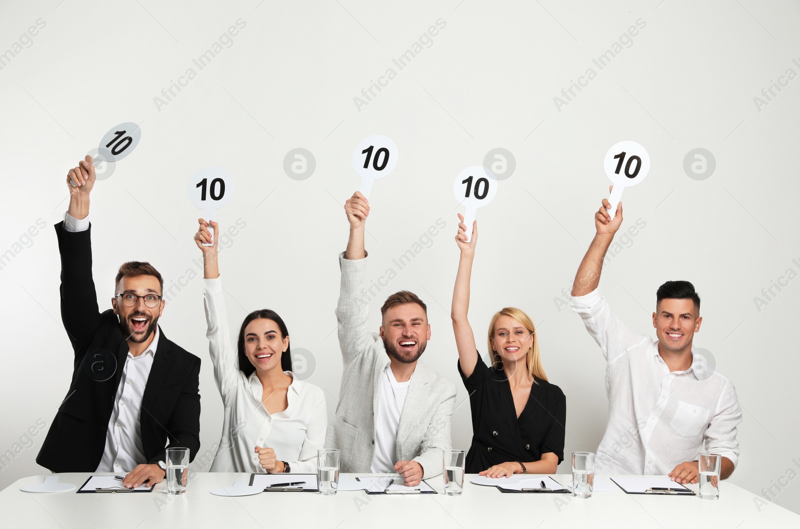 Photo of Panel of judges holding signs with highest score at table on white background