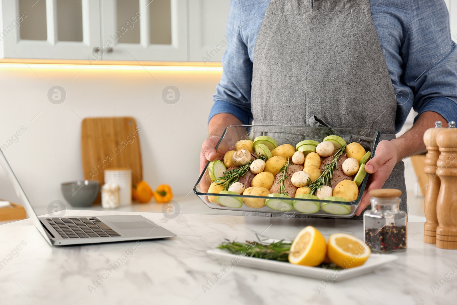 Photo of Man making dinner while watching online cooking course via laptop kitchen, closeup