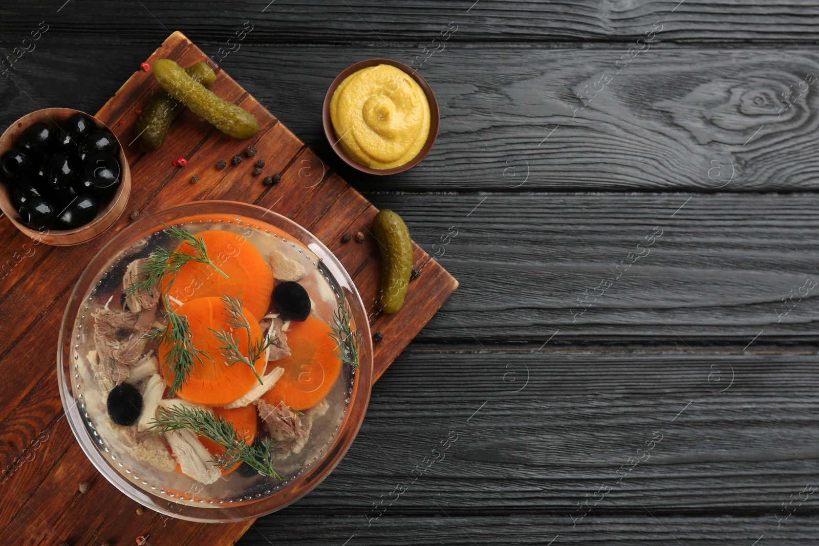 Photo of Delicious aspic with meat and ingredients on black wooden table, flat lay. Space for text