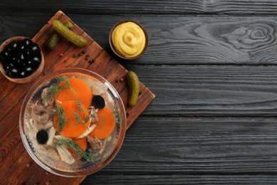 Photo of Delicious aspic with meat and ingredients on black wooden table, flat lay. Space for text