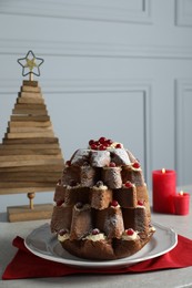 Photo of Delicious Pandoro Christmas tree cake with powdered sugar and berries near festive decor on white marble table
