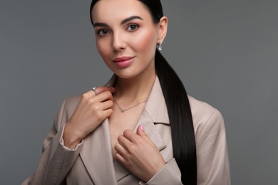 Photo of Beautiful young woman with elegant jewelry on dark grey background