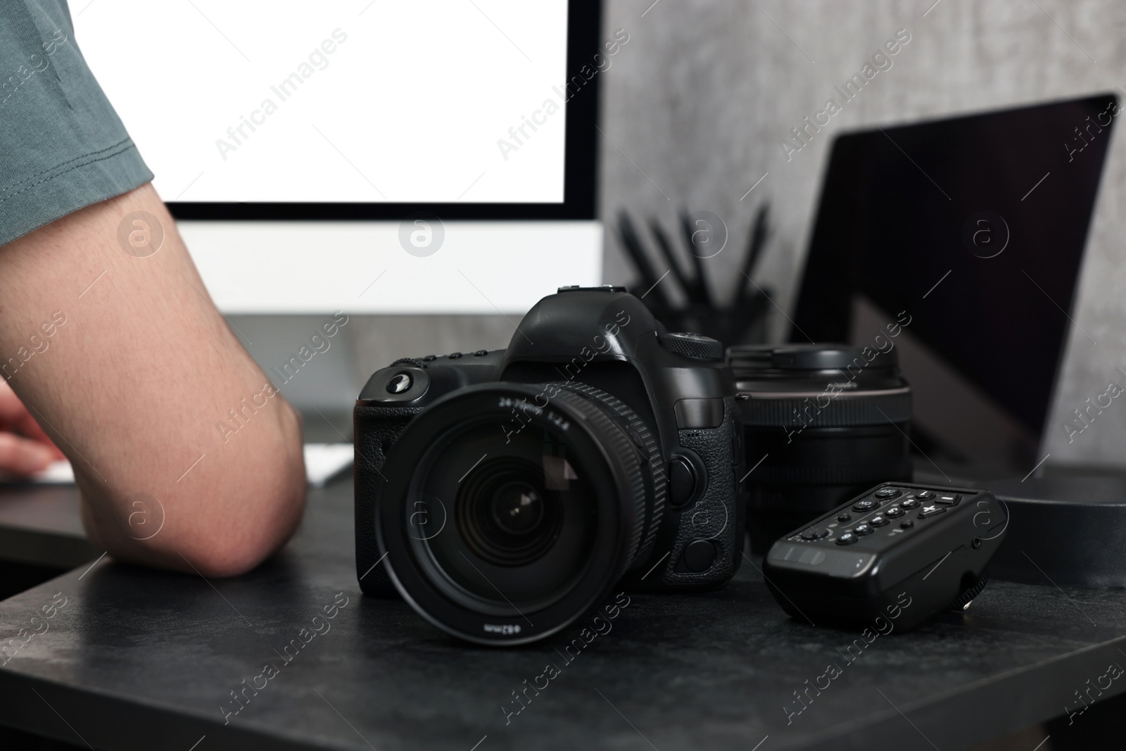 Photo of Camera on dark table, closeup. Photographer working with computer indoors, selective focus