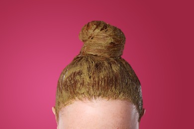 Young woman dyeing her hair with henna on pink background, closeup