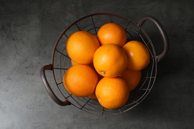 Photo of Basket with ripe oranges on grey background, top view