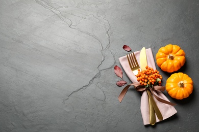 Photo of Cutlery, rowan berries and pumpkins on grey table, flat lay with space for text. Thanksgiving Day