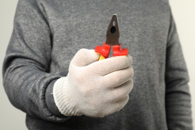 Photo of Man with combination pliers on light background, closeup