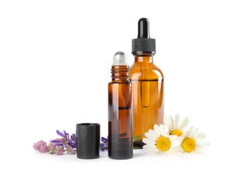 Photo of Bottles of herbal essential oils and wildflowers isolated on white